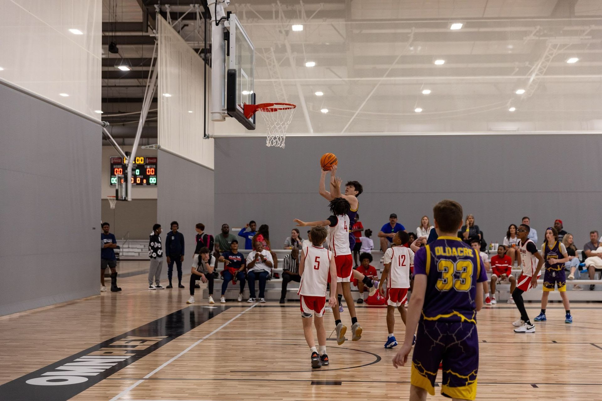 Basketball player shooting the ball, opponents attempting to block, in the OmniPlex.