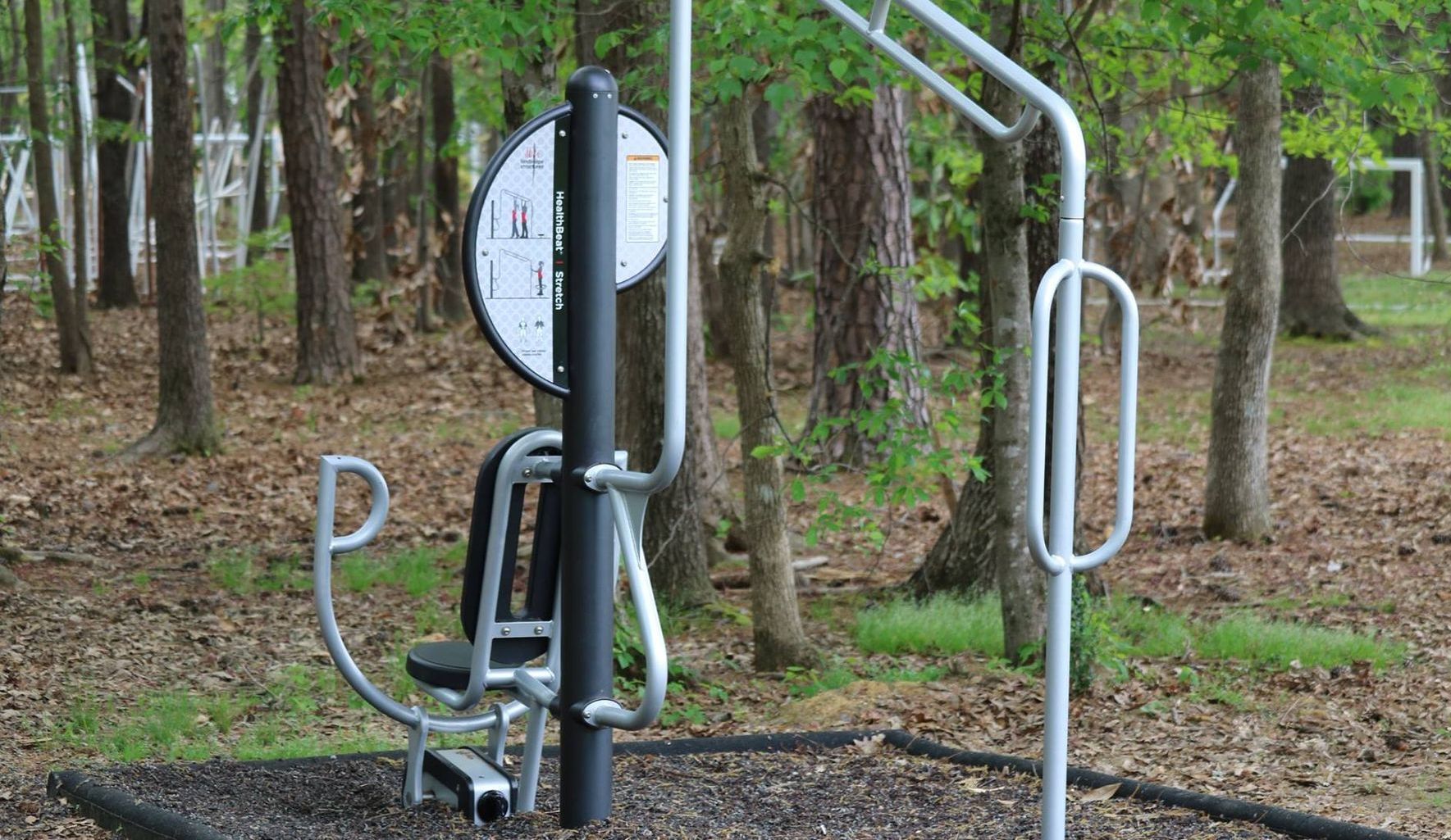 A park with a exercise machine in the middle of the woods.