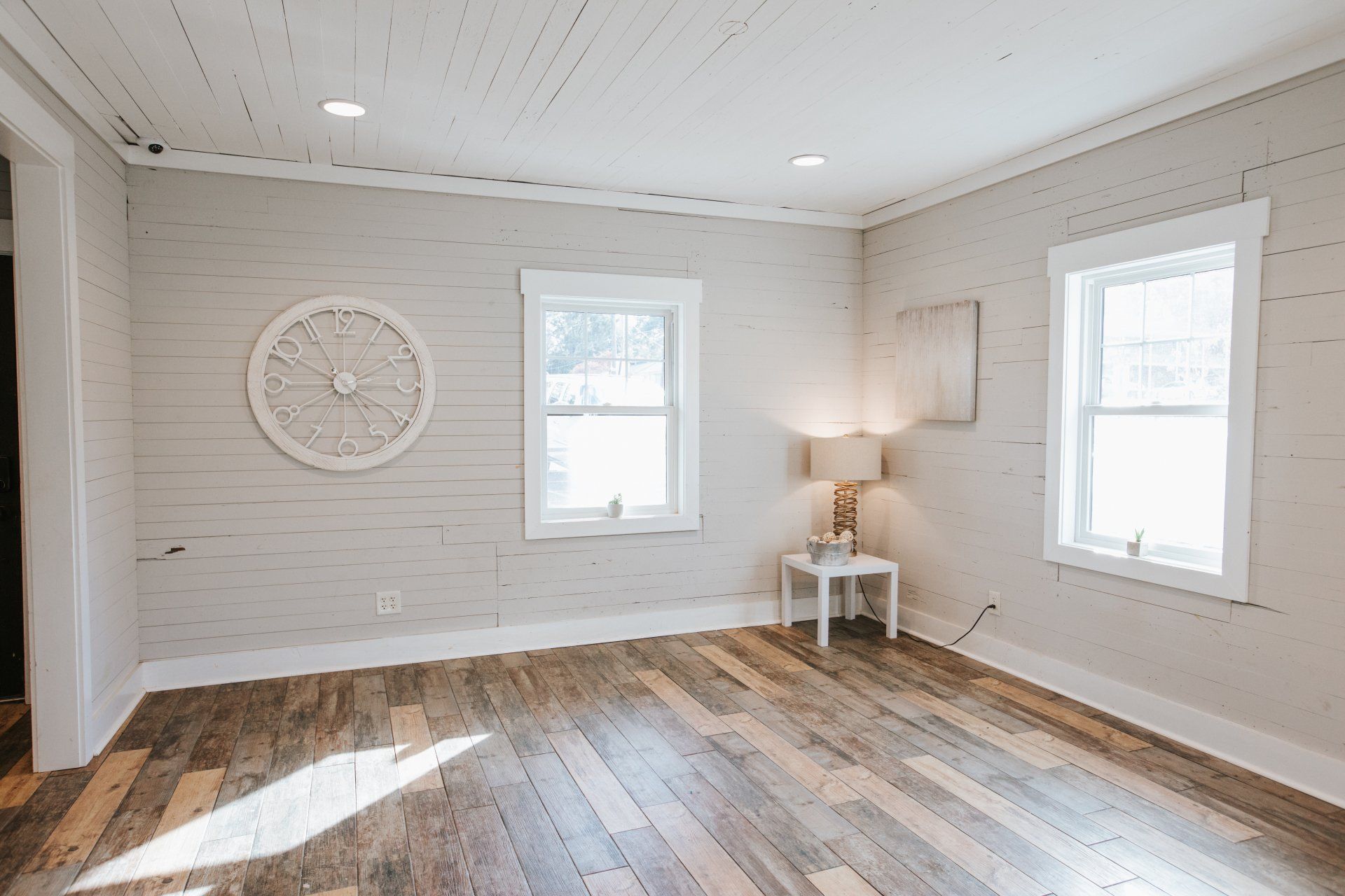 A living room with a wooden floor and a clock on the wall.