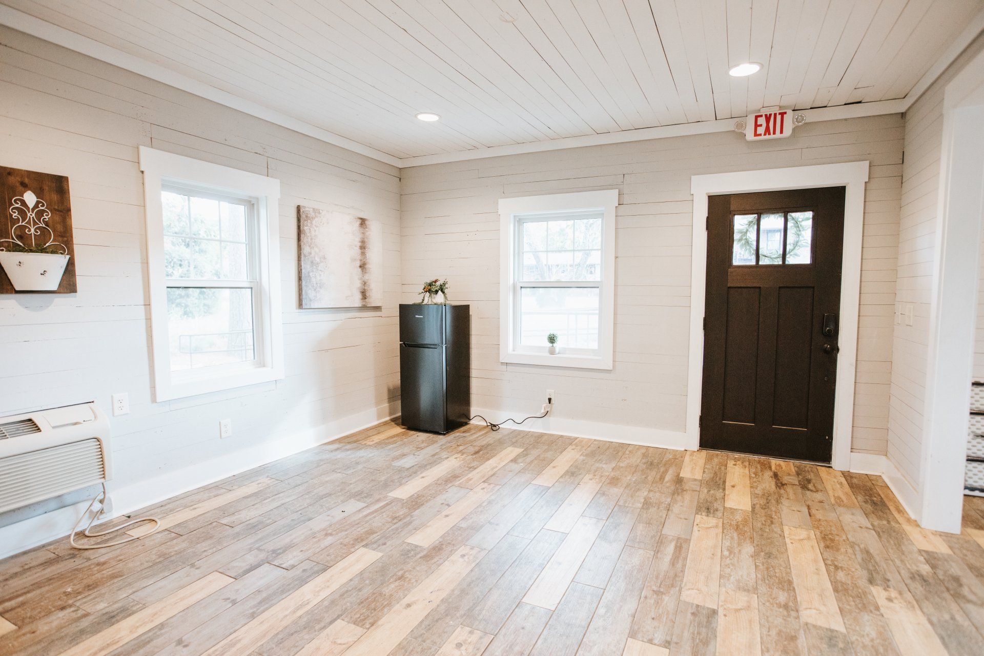An empty room with hardwood floors , a refrigerator , and a door.