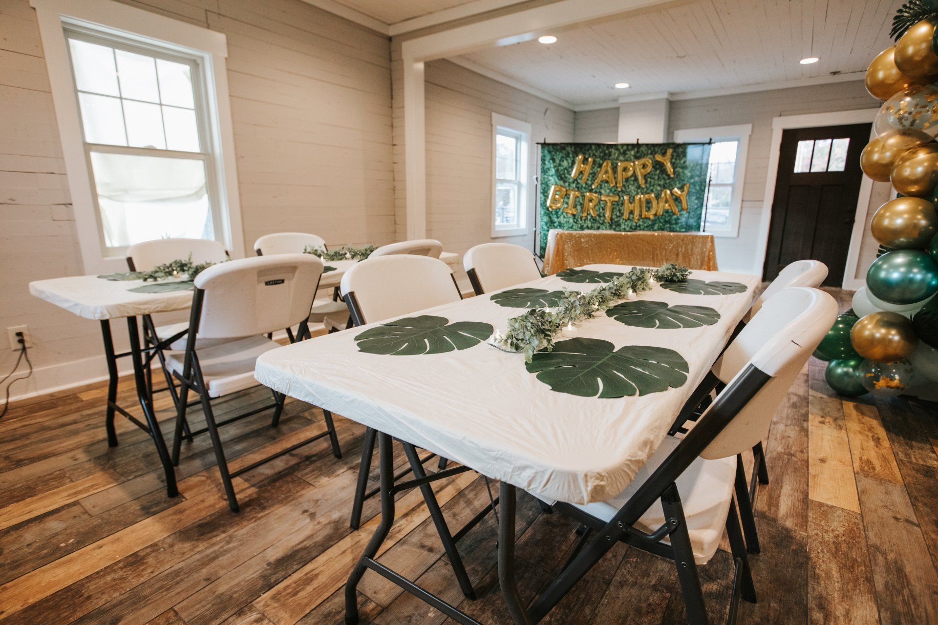 A room with tables and chairs set up for a birthday party.