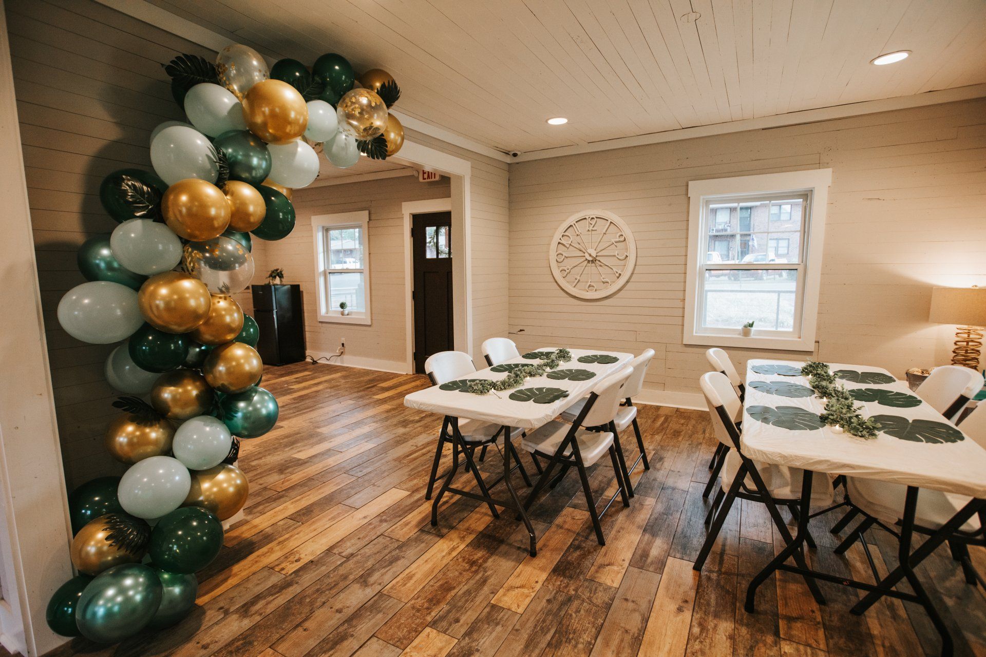 A room with tables and chairs and balloons on the wall.