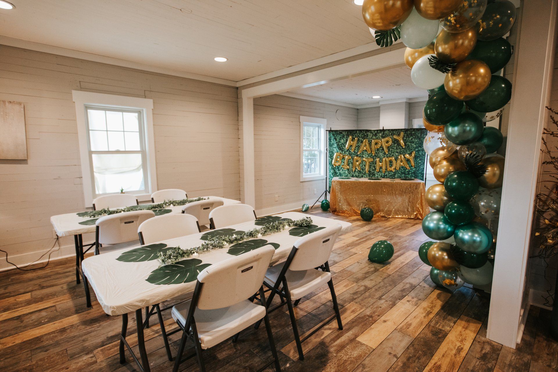 A room with tables and chairs and balloons on the wall.
