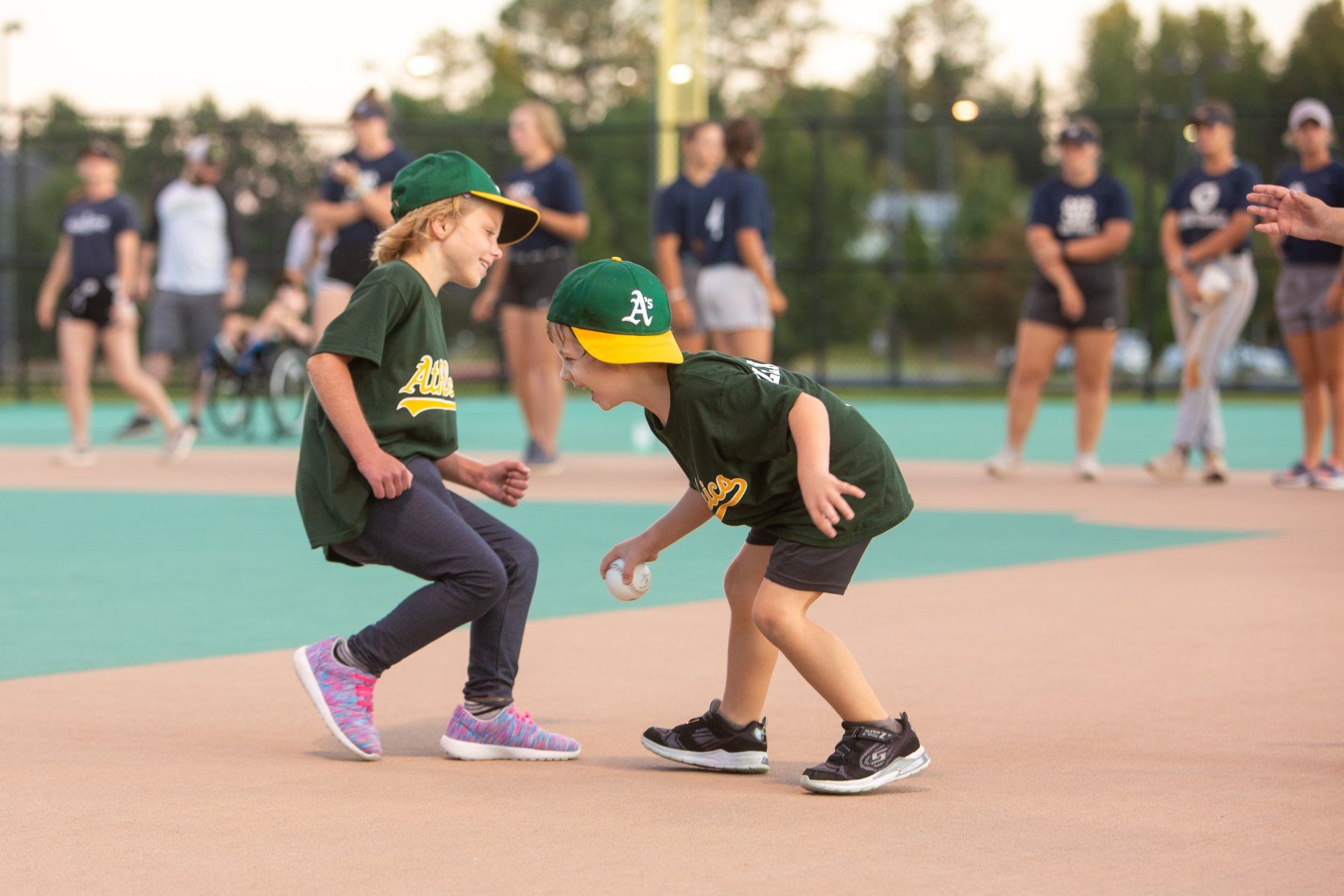 Two young girls are playing with a baseball on a baseball field.