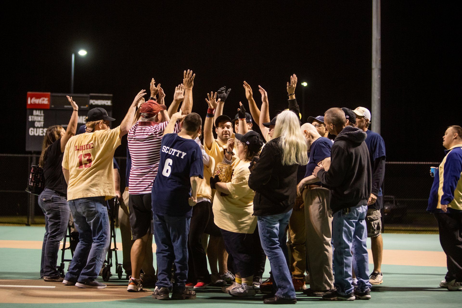 A group of people are standing in a huddle on a baseball field.