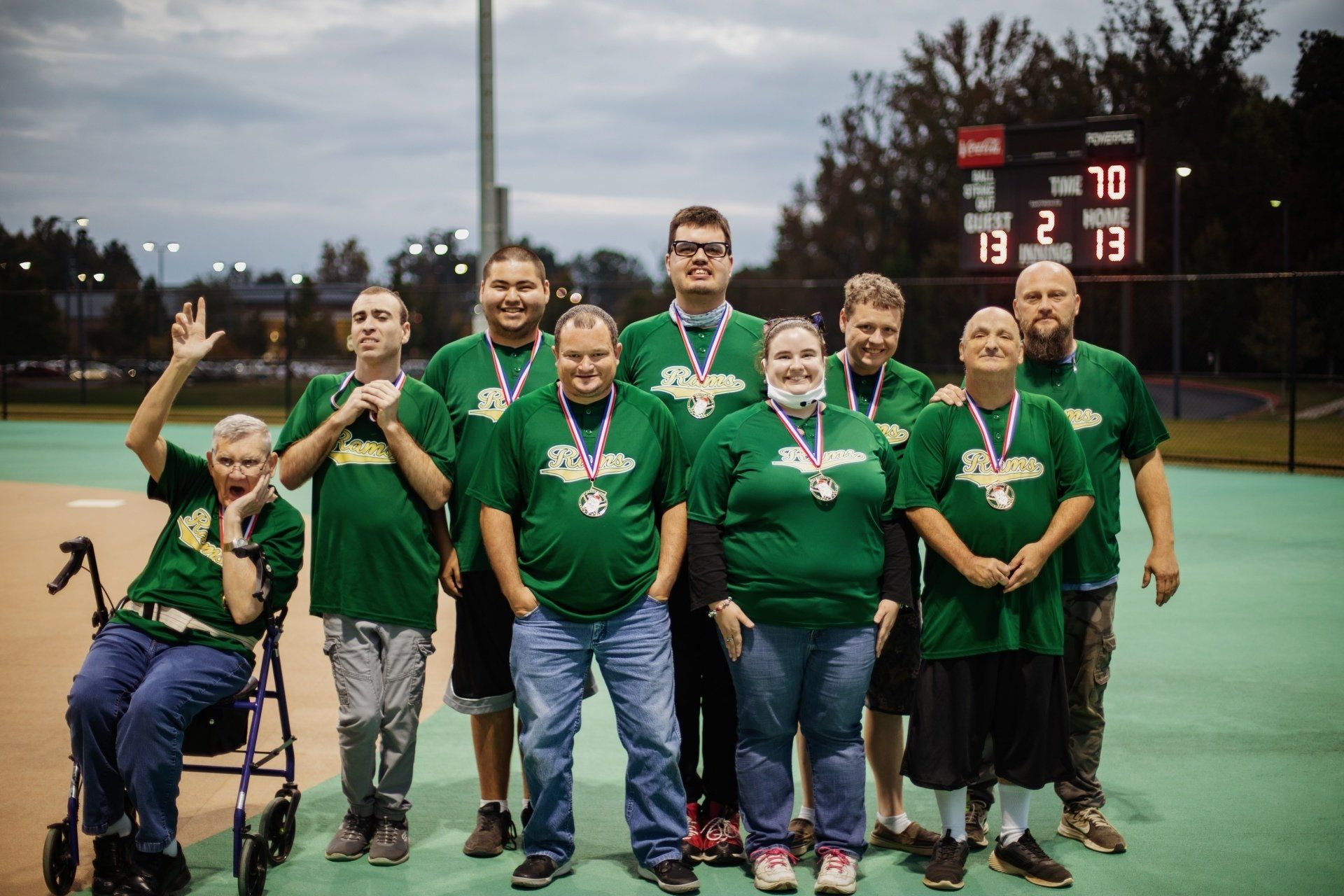 A group of people wearing green shirts and medals are posing for a picture.