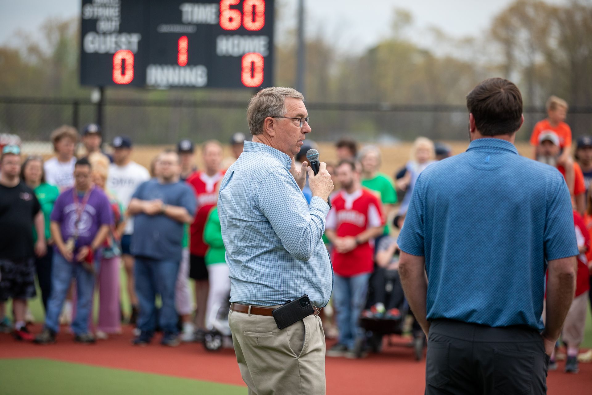 Two men are standing on a baseball field talking into microphones.