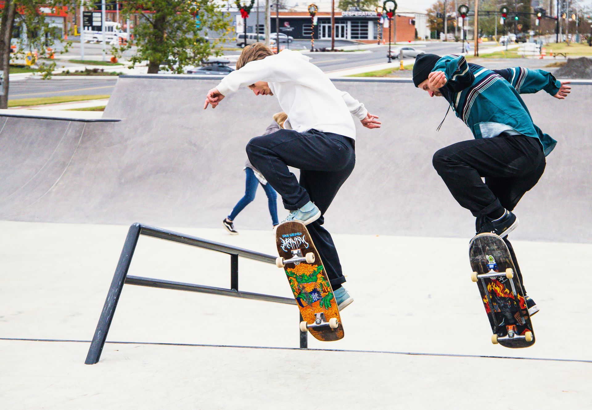 Two skateboarders are doing a trick on a railing at a skate park.