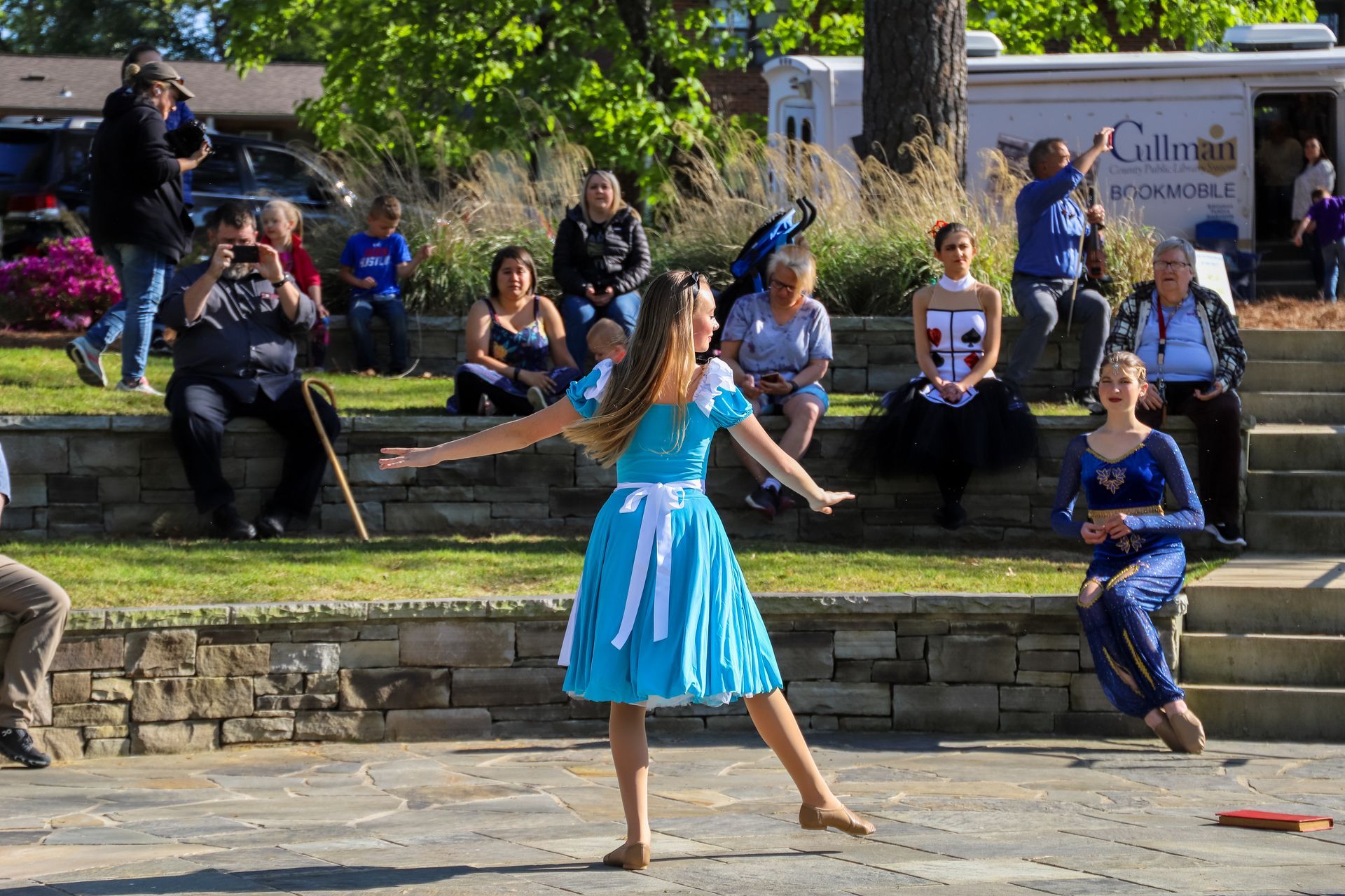 A woman in a blue dress is dancing in front of a crowd.
