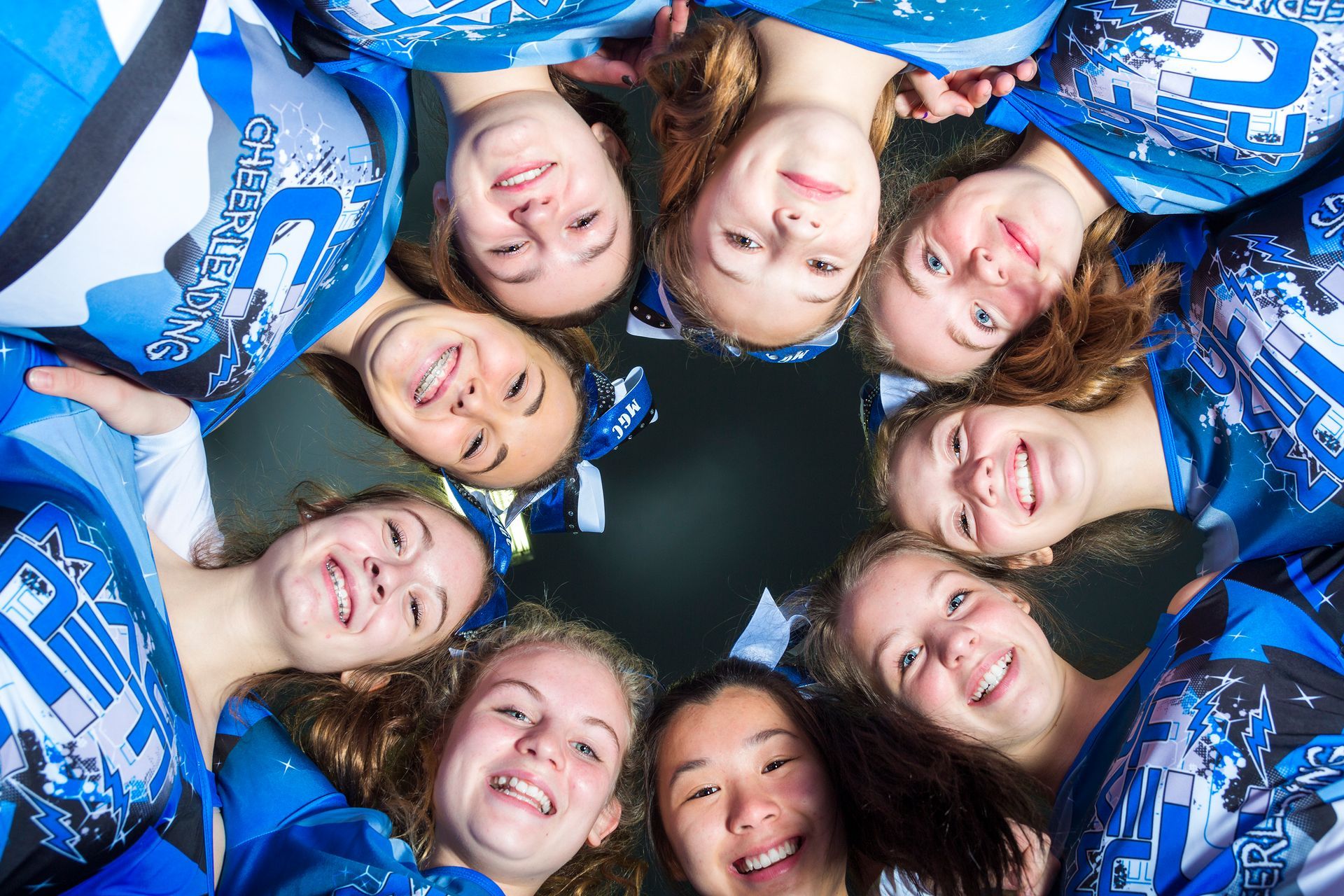 A group of cheerleaders are posing for a picture in a circle.