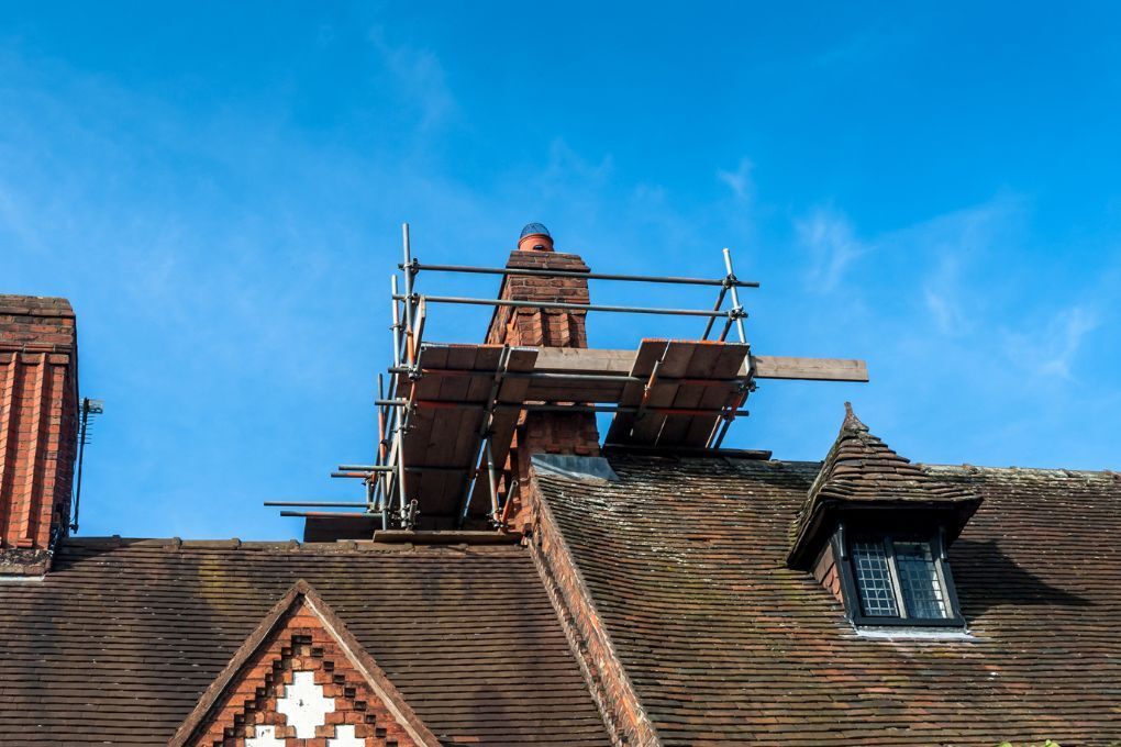 Roofers Kilmarnock repairing the pointing on a chimney using scaffolding