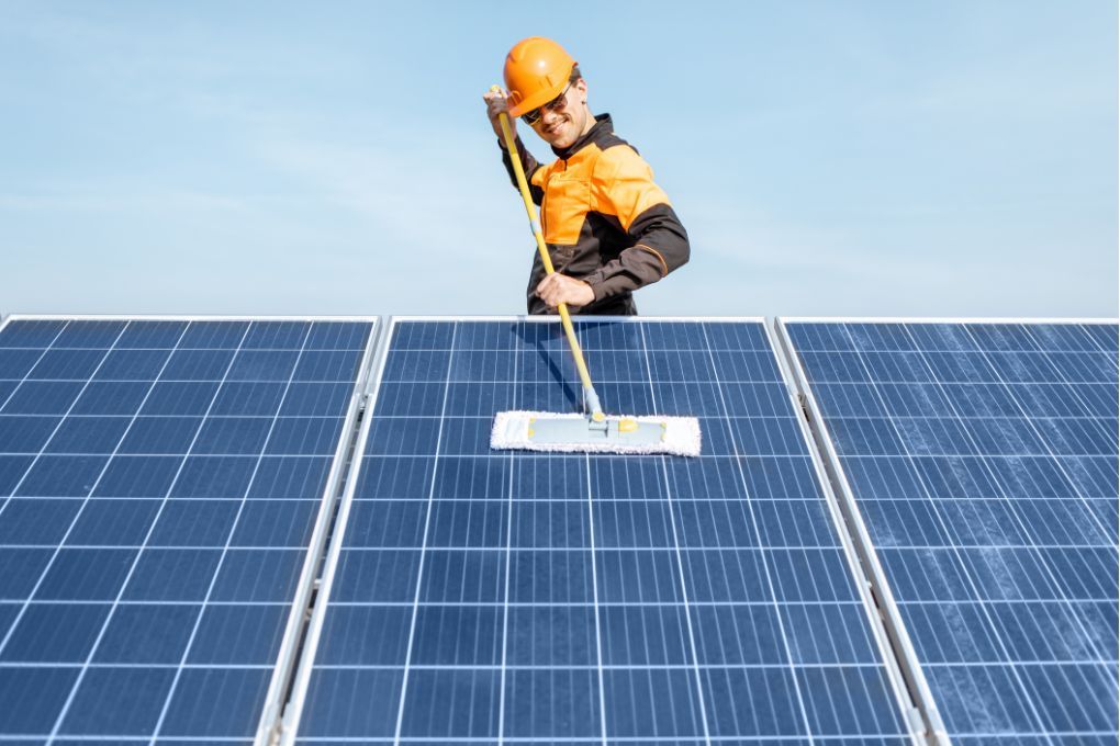 Roofers Kilmarnock cleaning a solar panels on a roof with an extended wiper