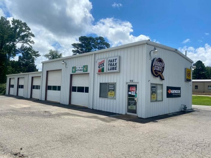 White auto repair shop with garage bays and signs under a blue sky