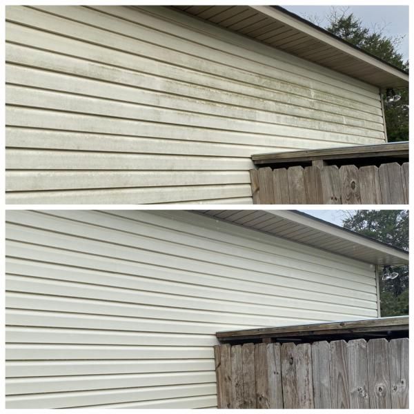 Before-and-after view of a house exterior with cleaner white siding above a weathered wooden fence.