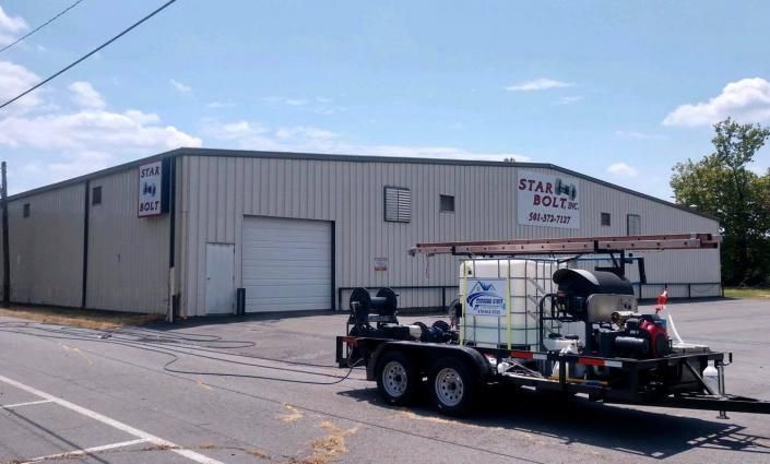 Gray industrial building with a trailer parked outside under a blue sky