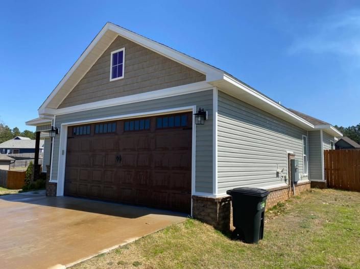 Single-story gray house with a dark brown garage door under a blue sky