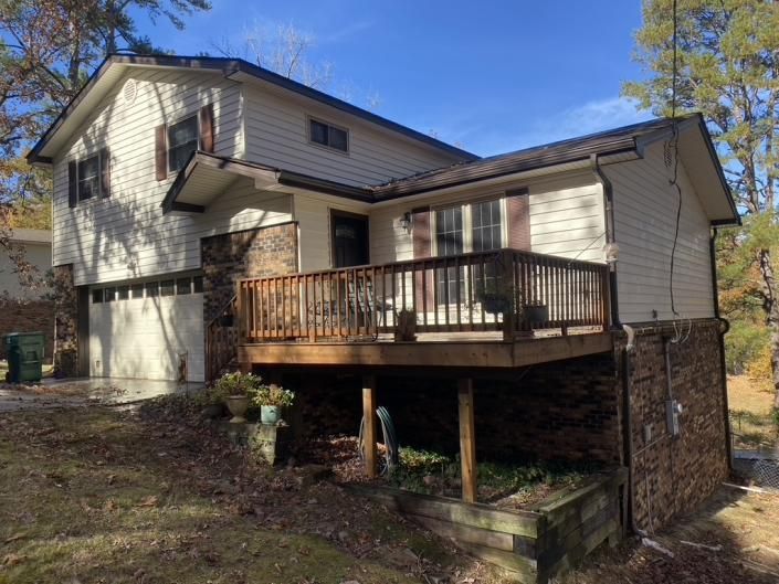 Suburban house with a wooden deck and stone supports on a wooded hillside