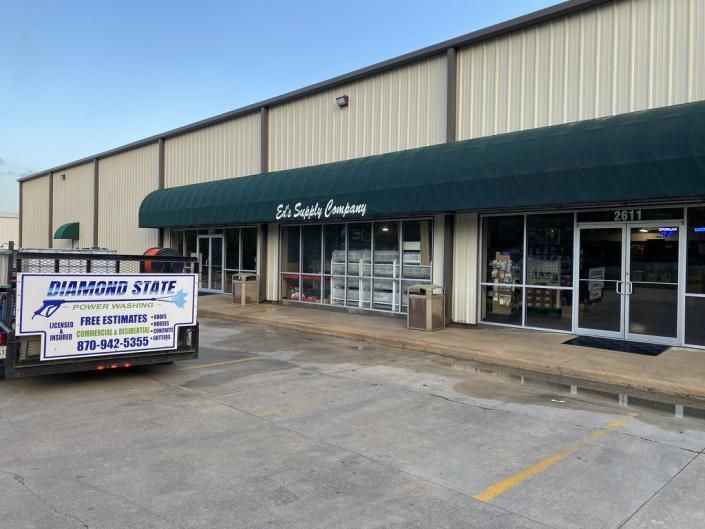 Strip mall storefront with green awning and a moving truck parked outside