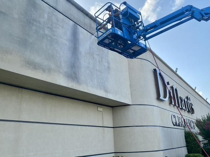 Blue lift platform raised beside a building with a “C” sign and cloudy sky