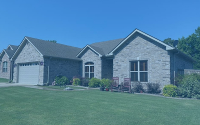 Brick suburban house with a two-car garage, manicured lawn, and blue sky