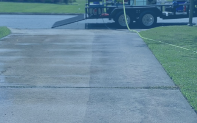 Concrete driveway beside a lawn, with a utility truck and hose in the background.
