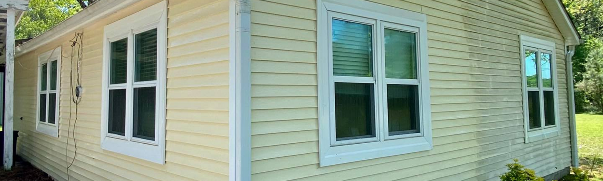 Yellow house siding with white-trimmed windows and a corner view of the exterior