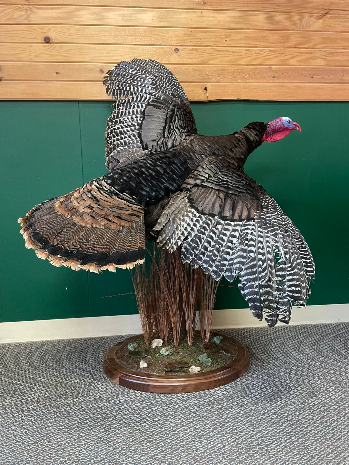A stuffed turkey is sitting on top of a tree stump.