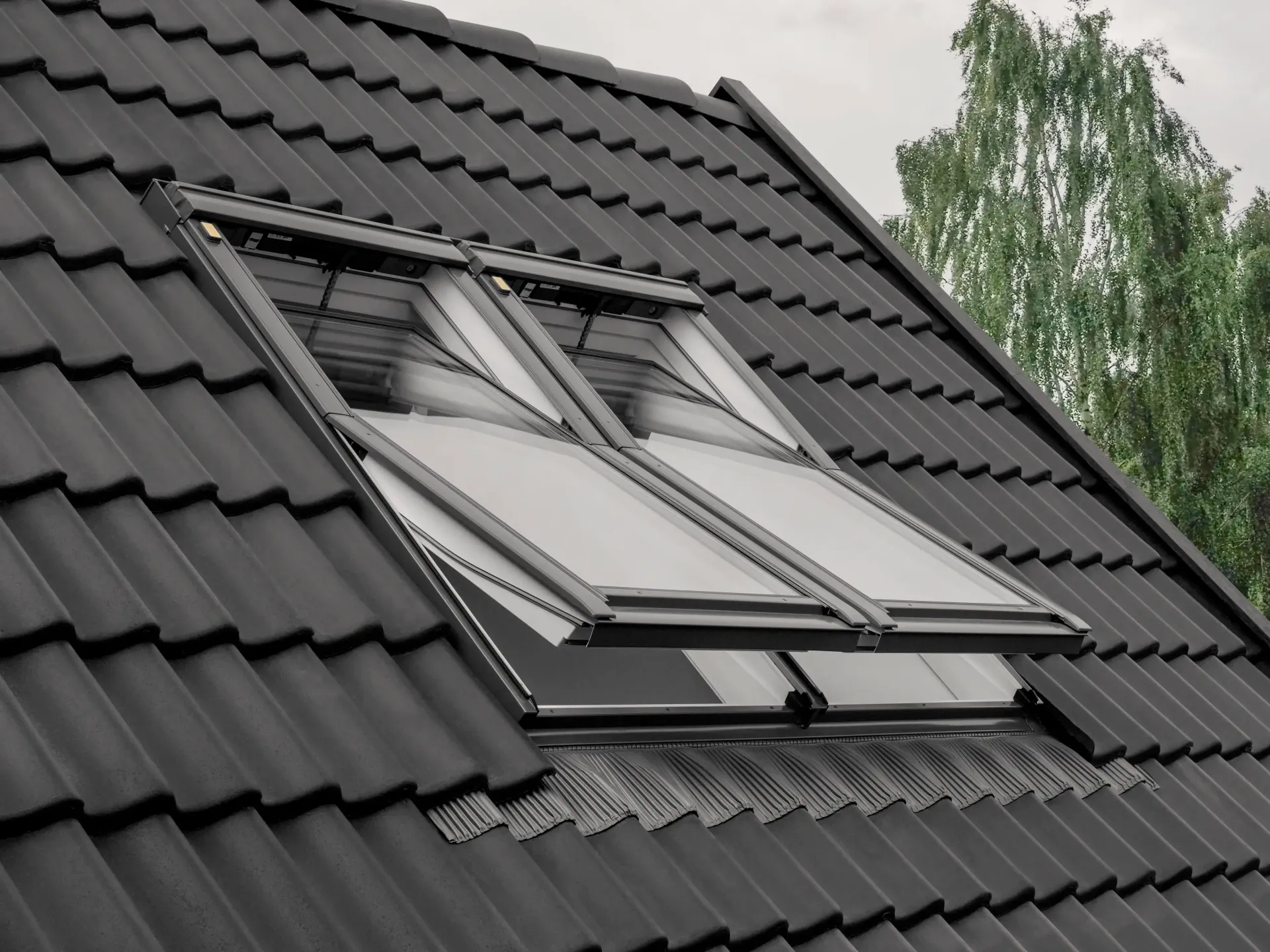 Black tiled roof with a skylight window under a cloudy sky