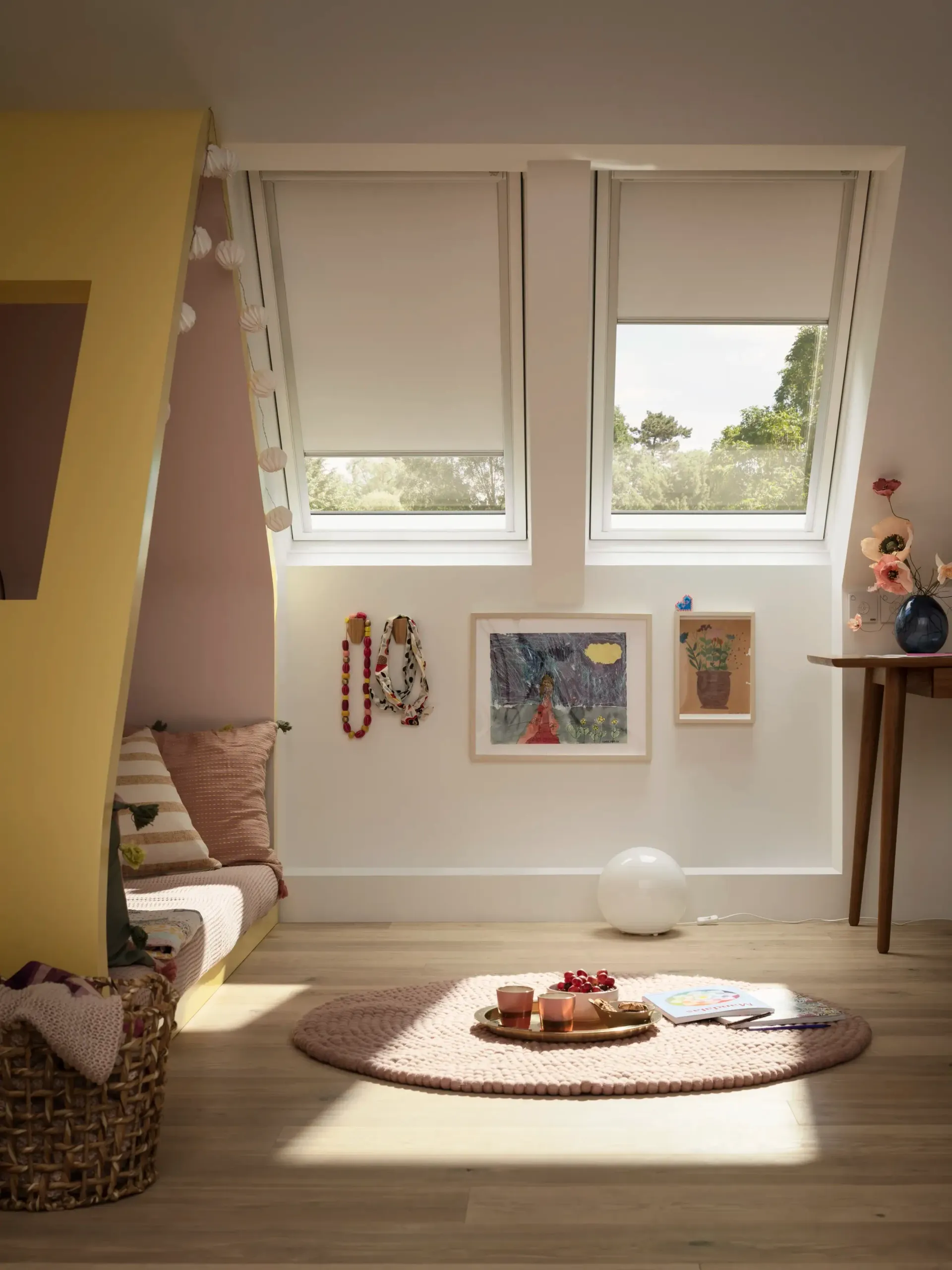 Bright sunlit room with open windows, a low round rug, and children's toys and art on the wall.