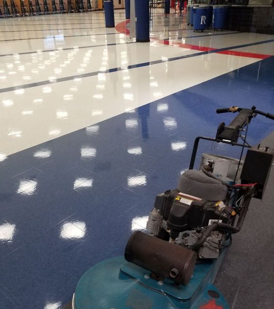 Small wheeled robot on a glossy blue gym floor with white tiles and red boundary lines