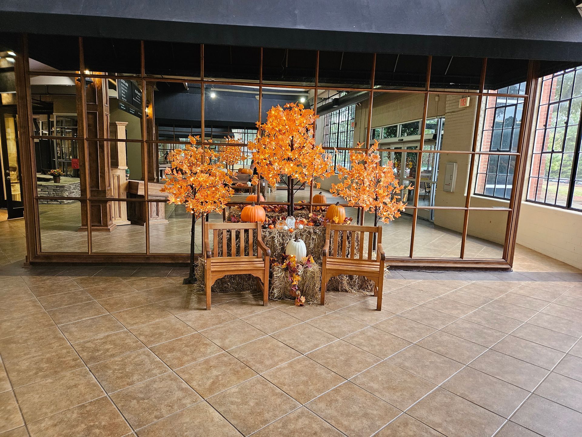 Indoor lobby with a wooden bench and orange floral arrangement in front of glass doors