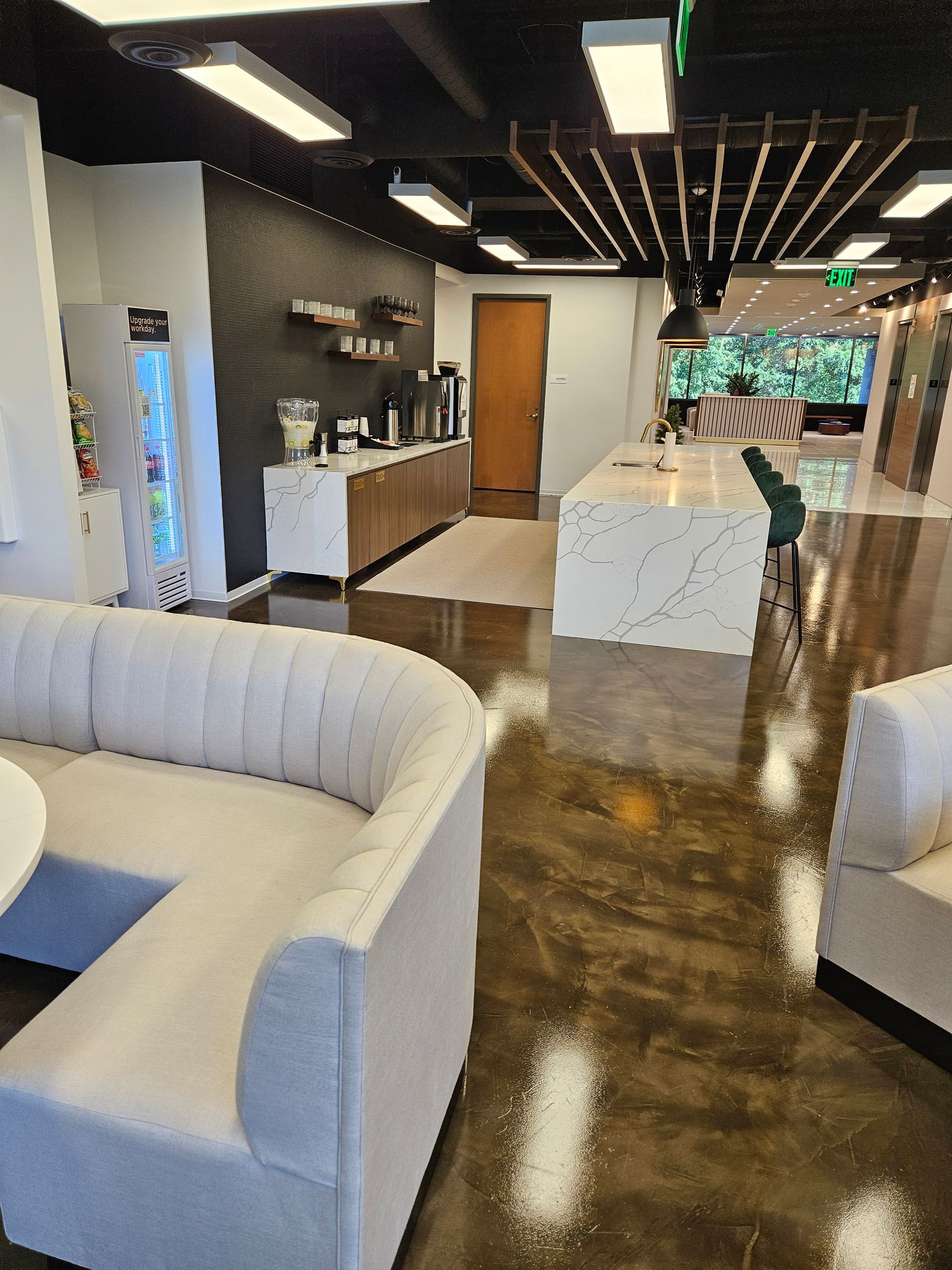 Modern salon with white couches, black ceiling lights, and a marble reception table