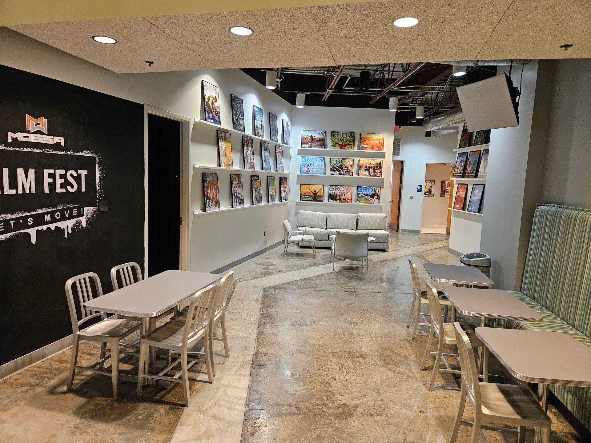 Modern art gallery booth with black “LM FEST” wall, display panels, and benches along a curved hallway