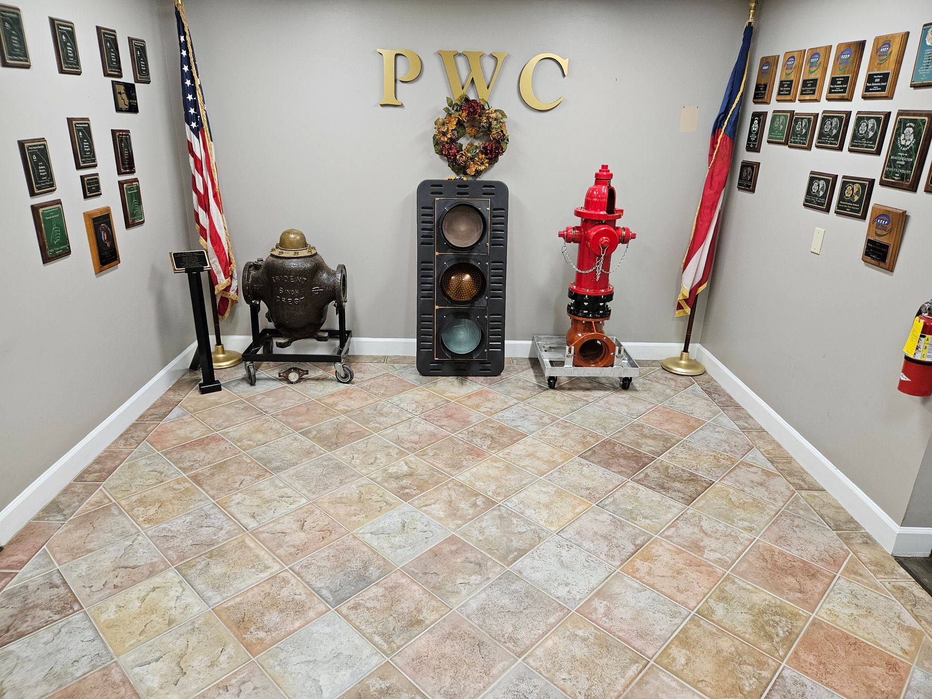 Office display room with trophies, plaques, and a red fire hydrant statue on tiled floor