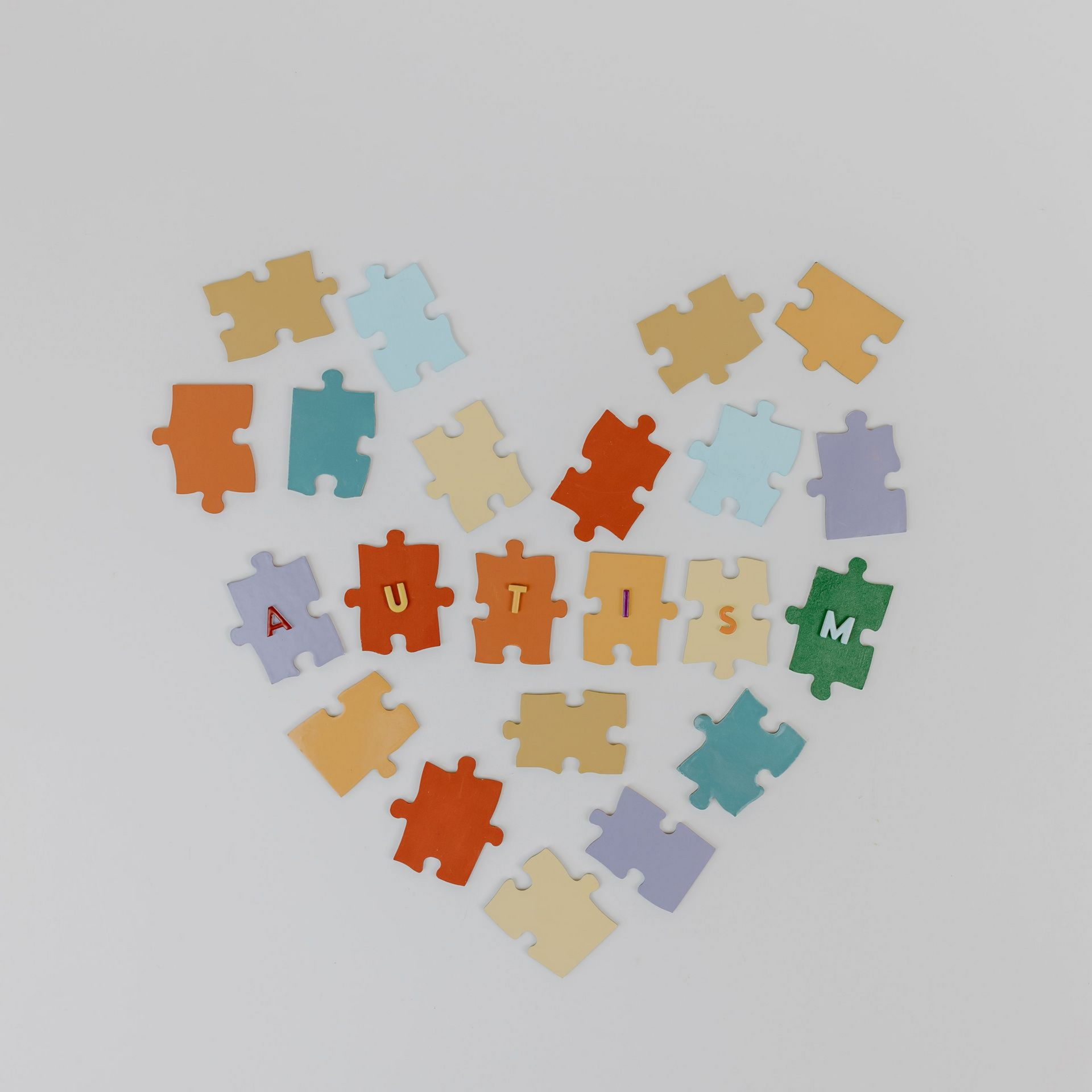 Heart shape made of colorful puzzle pieces on a light gray background.