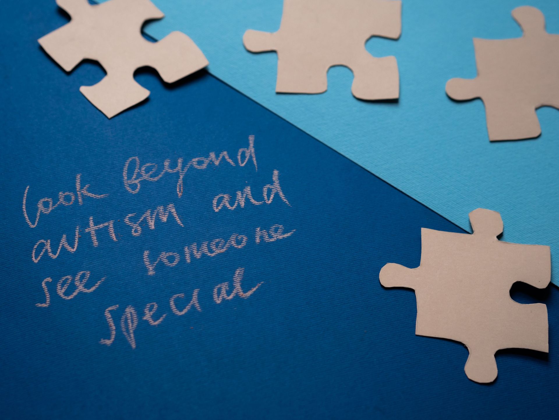 Puzzle pieces around a blue note reading “Look beyond autism and see how much special”