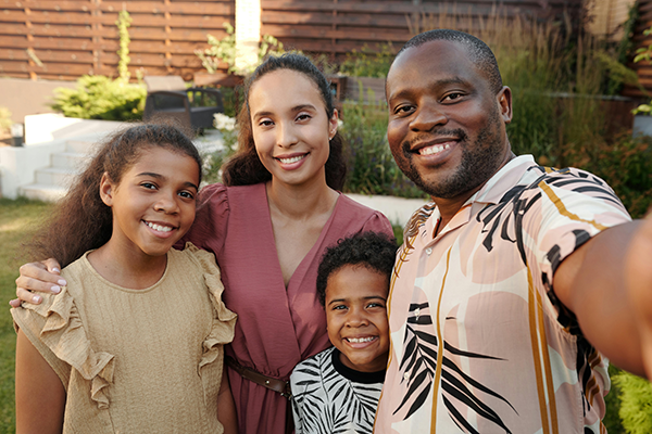 Smiling family taking a selfie together in a backyard garden