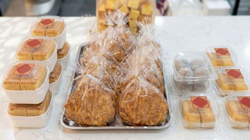 Assorted packaged pastries and muffins displayed on trays at a bakery counter