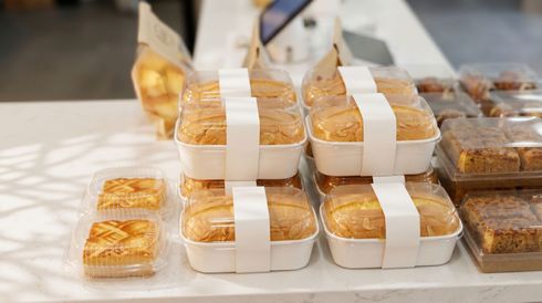 Stacked white takeout containers filled with pastries on a table