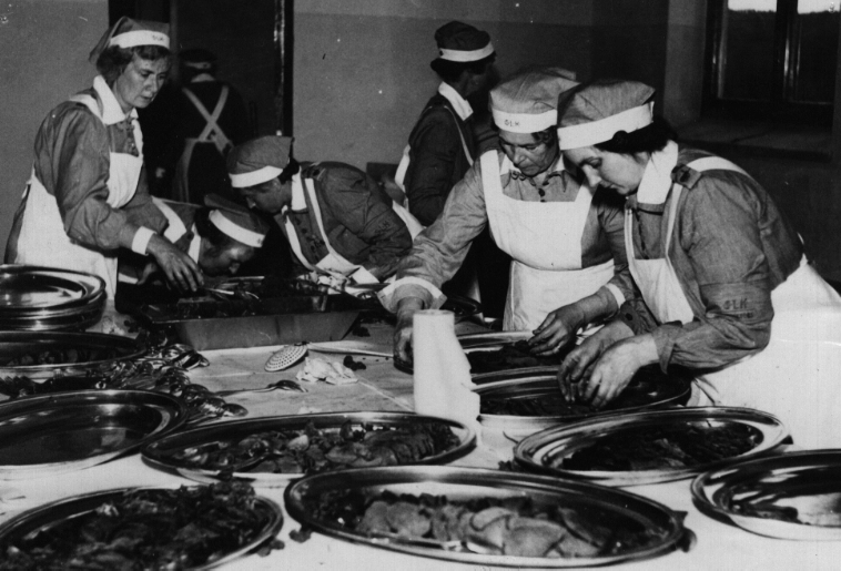 Ett svartvitt foto av en grupp människor som lagar mat