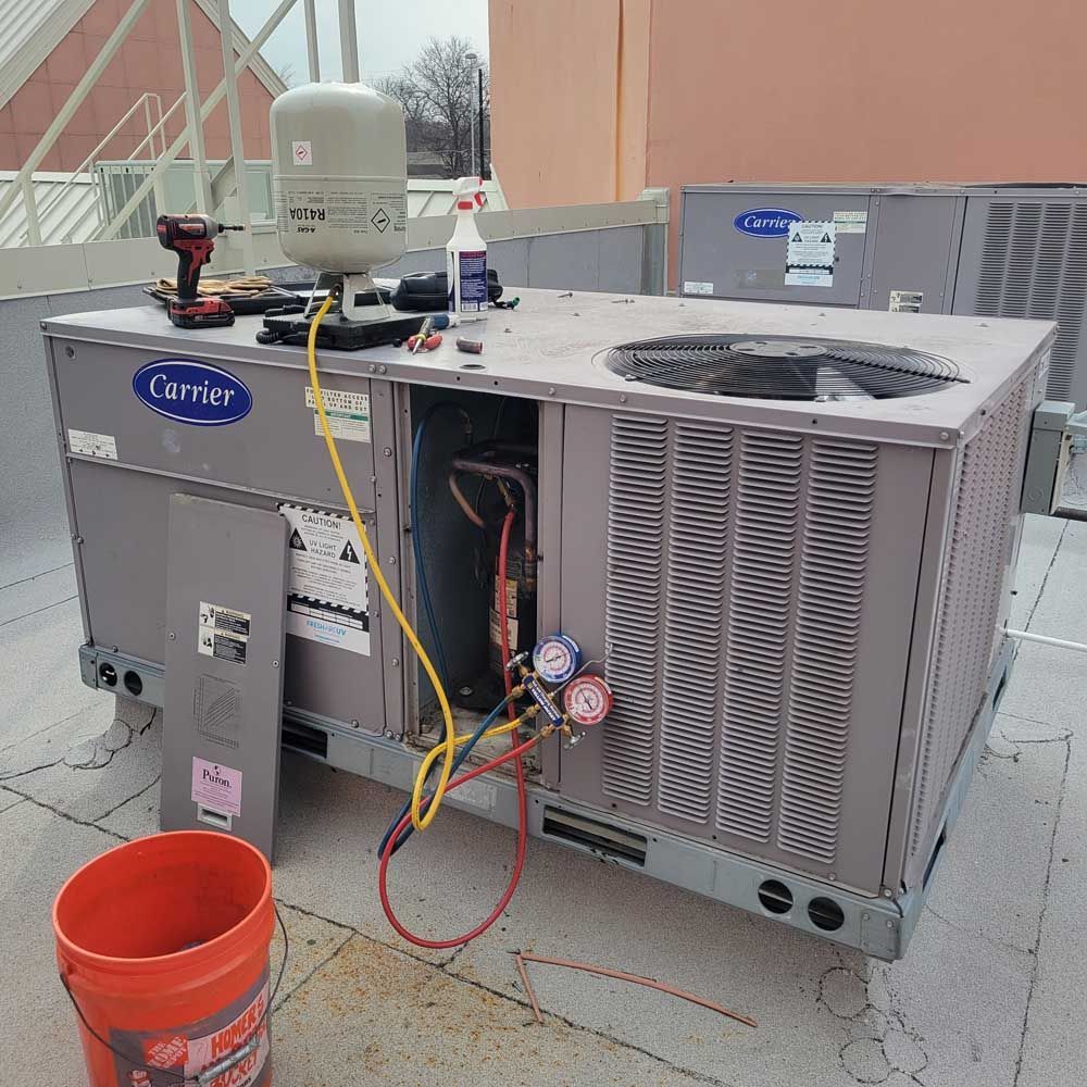 Exterior air conditioner unit mounted on a white building against a blue sky