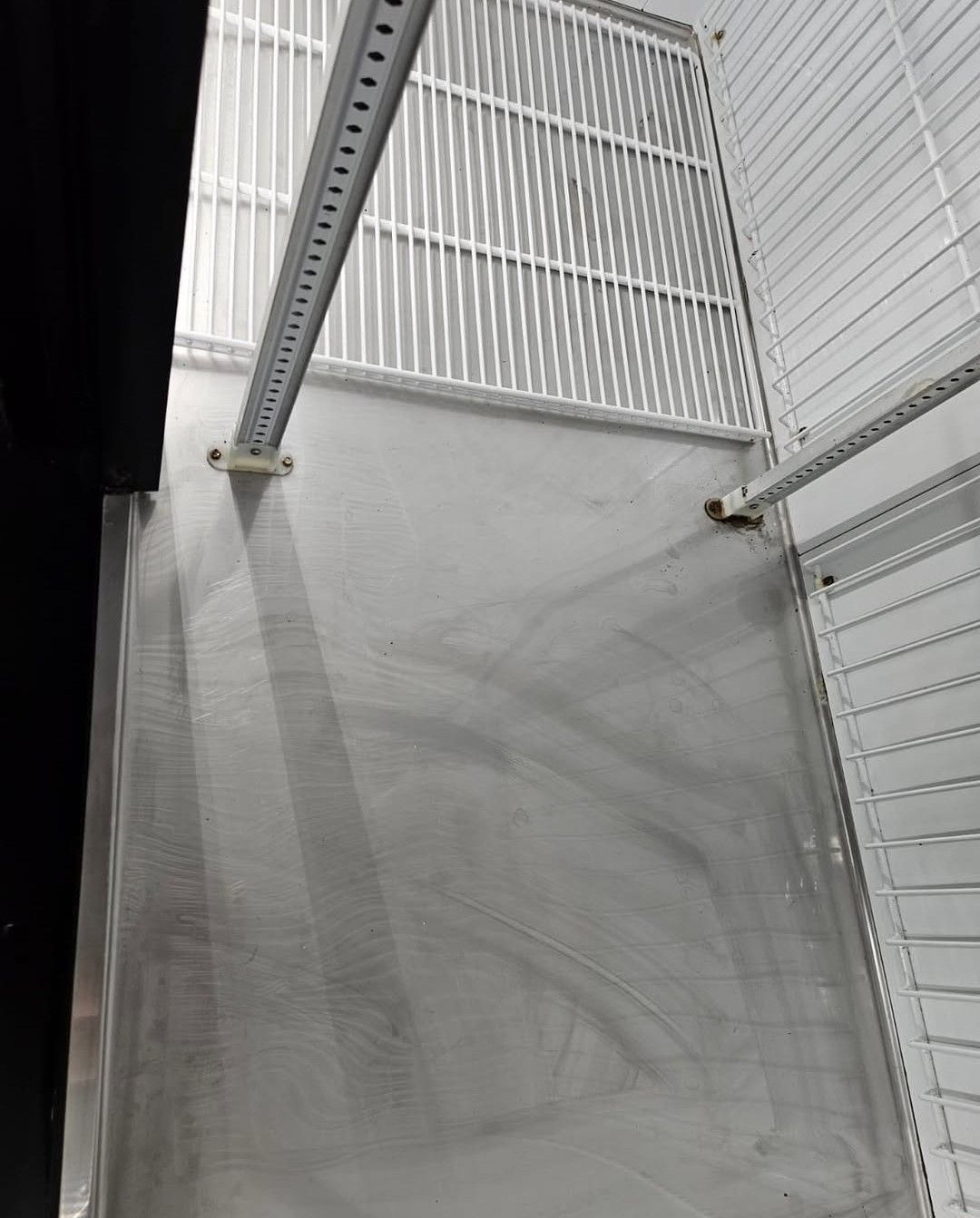 A low-angle view of a white, industrial-style refrigerated display case interior with metal wall shelving tracks.