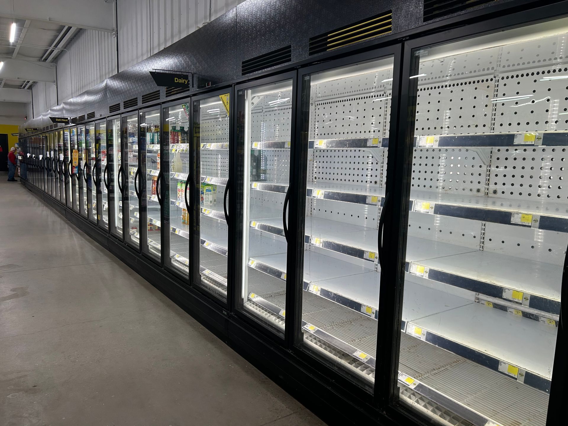 A long row of empty grocery store freezer display cases with black frames and interior LED lighting.
