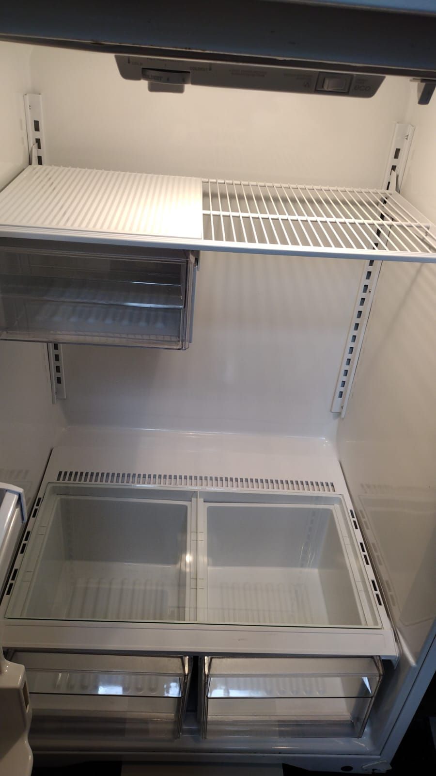 An empty refrigerator interior featuring adjustable shelves and two clear drawers at the bottom.