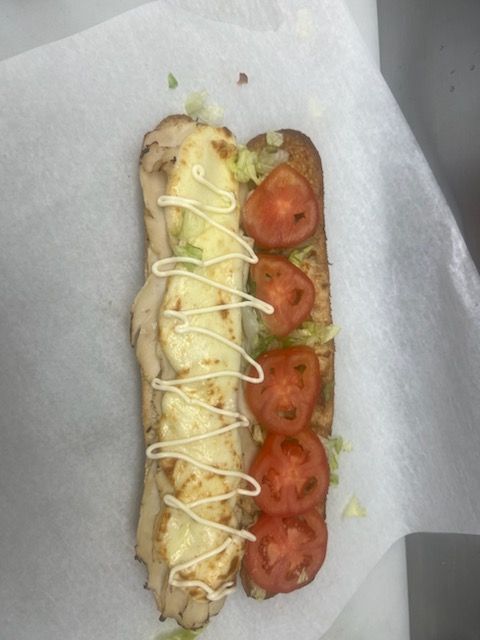 A sub sandwich with mayonnaise and tomatoes on it