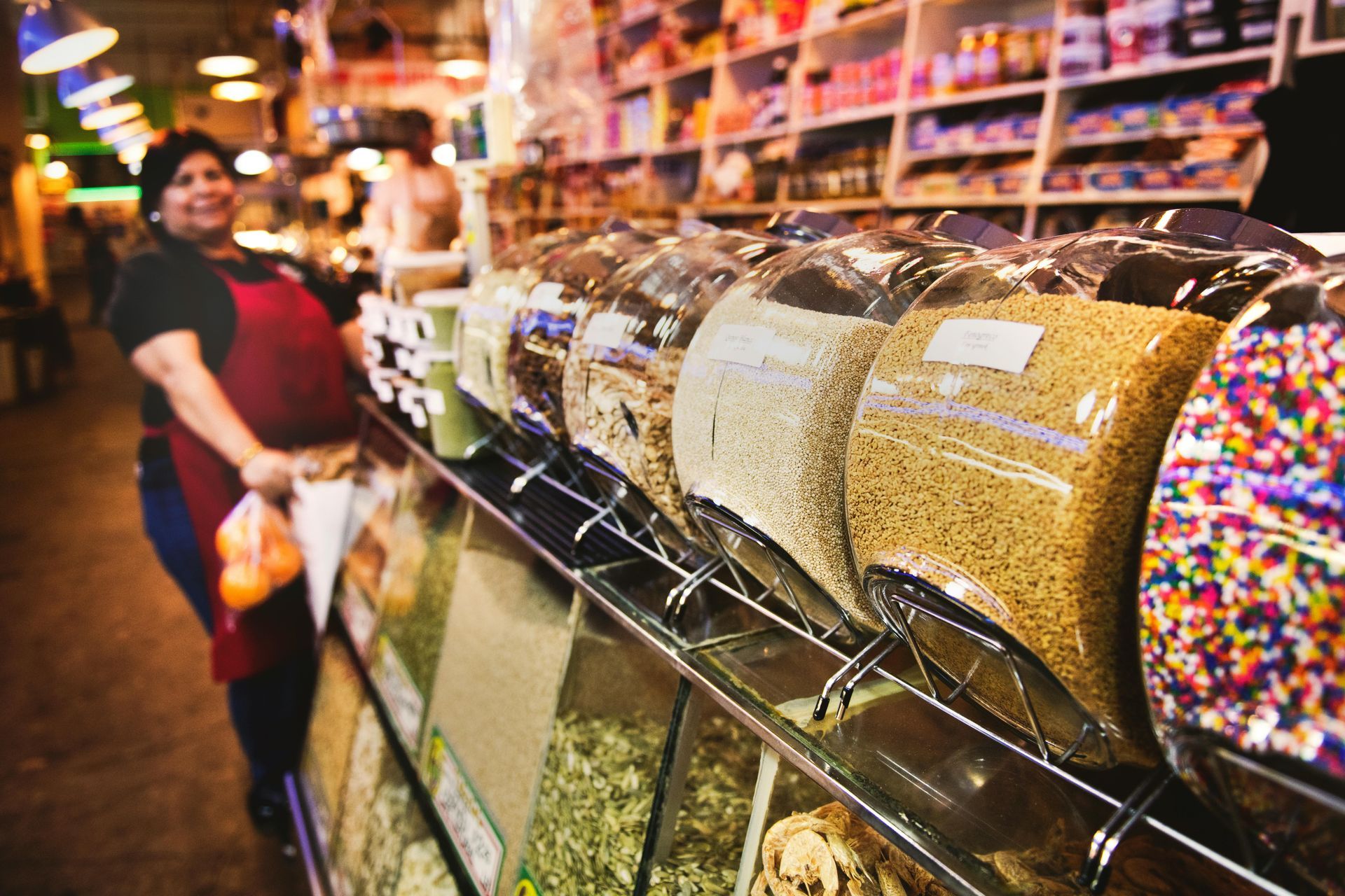 Une femme se tient devant un étalage de noix et de vermicelles dans un magasin.