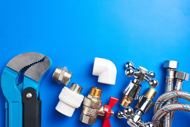 Plumber’s tools and pipe fittings on a bright blue background
