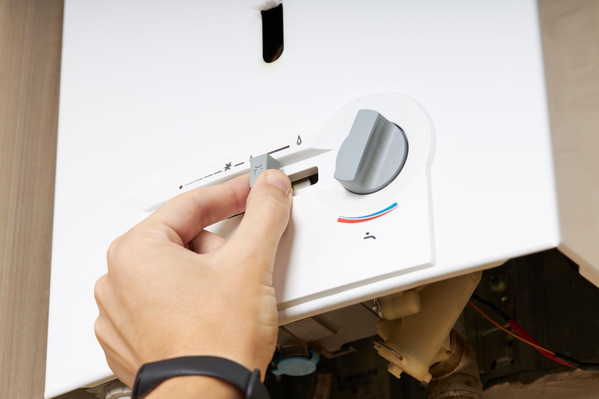 Hand adjusting a white appliance control knob near a black switch.