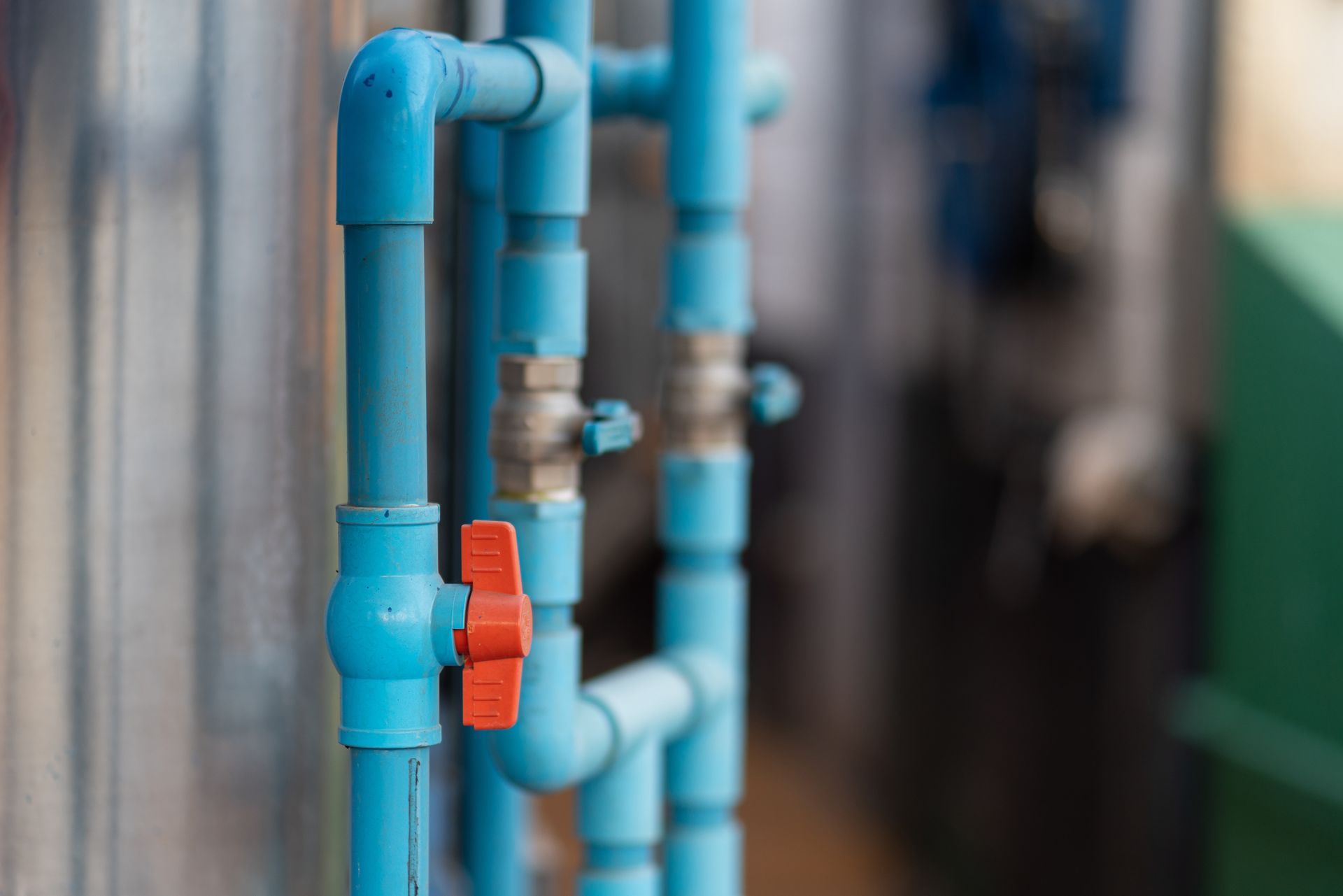 Blue and light-blue pipes with a red valve in an industrial corridor