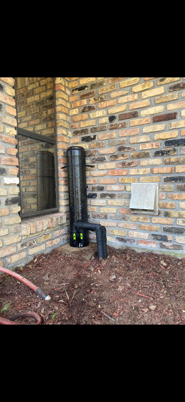 Brick porch corner with black utility pipes, meter box, and mulched ground under a covered overhang